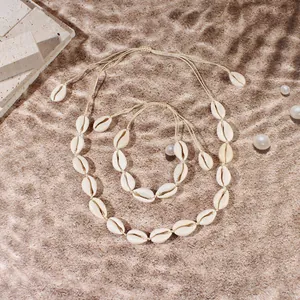 Dettaglio di set collana e bracciale con conchiglie intrecciate su fondo testurizzato