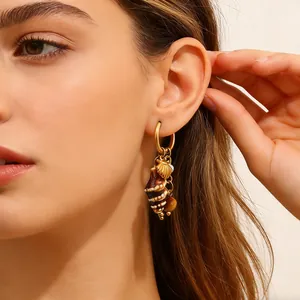 Elegant gold hoop earring featuring natural conch and seashell charms worn by a model