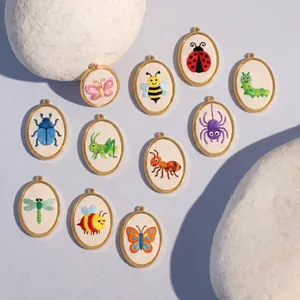 Detailed view of eleven assorted oval pendants with vibrant insect embroidery motifs