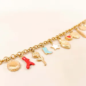 Close-up of 18K gold plated charm chain with heart, star, and boot pendants.