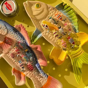 Close-up of colorful beaded fish charms with silver lobster clasps for ocean style DIY jewelry