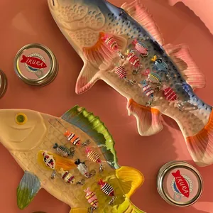 Detailed macro view of colorful ocean style beaded fish DIY pendants on decorative plates
