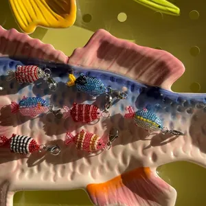 Detailed view of colorful handmade beaded fish charms featuring metal lobster clasps for DIY