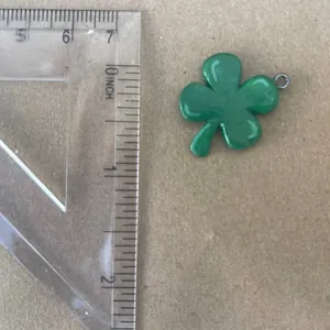 Close-up detail showing the size measurement of a green four-leaf clover resin pendant charm