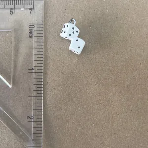 Macro view of white dice pendant charm with clear ruler showing its 0.75-inch size