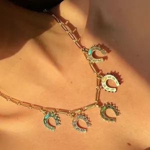 Macro view of stainless steel necklace featuring colorful horseshoe pendants with vibrant stones.
