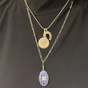 Detailed view of layered gold stainless steel necklaces with bee and horseshoe charms