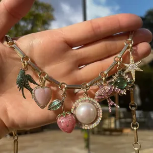 Gros plan d'un collier doré avec breloques de luxe en forme de fraise et d'étoile