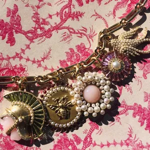 Vue détaillée d'un collier vintage doré avec breloques de perles et motifs d'abeilles