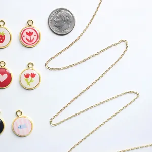 Bunte emaillierte Anhänger mit Blumen- und Herzmotiven und goldener Halskette.