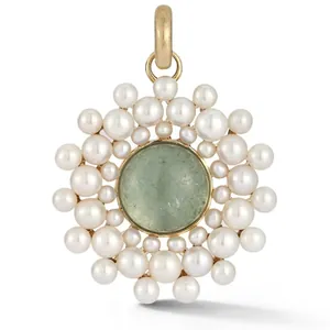 Détail d'un pendentif soleil avec pierre verte centrale et perles blanches autour.