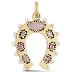 Detailed macro view of a gold-plated horseshoe pendant with pearls and pink gemstones.