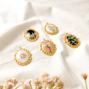 Detailed view of five vintage oval floral pendants with gold filigree edges on white fabric