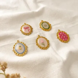 Close-up of vintage oval pendants featuring bow, flower, and fruit enamel designs