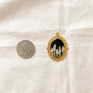 Detailed vintage gold floral pendant next to a quarter coin for size comparison