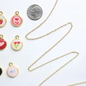 Detailansicht bunter Emaille-Anhänger und Goldkette mit Münze als Größenvergleich
