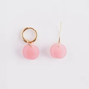 Detailed view of gold stainless steel hoop earrings with pink translucent round pendants