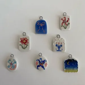 Lot de sept pendentifs en céramique faits main aux motifs fleurs, papillons et lune