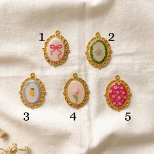 Detail of five vintage oval stainless steel pendants with bow and floral patterns.