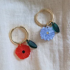 Detail of handmade stainless steel hoop earrings with colorful resin flower charms