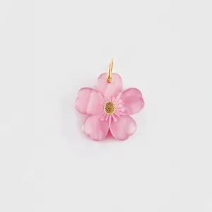 Close-up macro view of a pink translucent flower pendant with a golden center for DIY jewelry