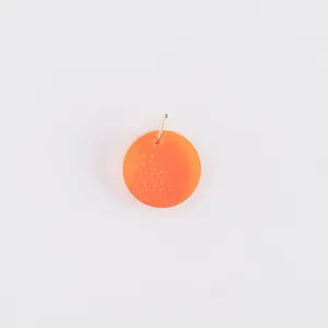 Macro view of a translucent orange acrylic fruit pendant charm for DIY jewelry accessories.