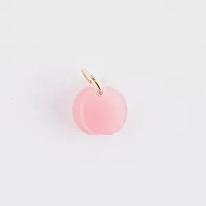 High-quality detail of a pink peach-shaped acrylic pendant for DIY jewelry making