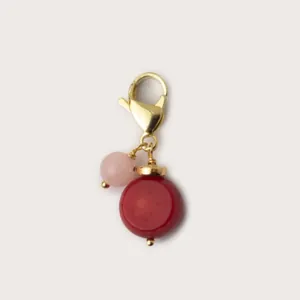Primo piano di un ciondolo fatto a mano con perla a disco rossa e rosa