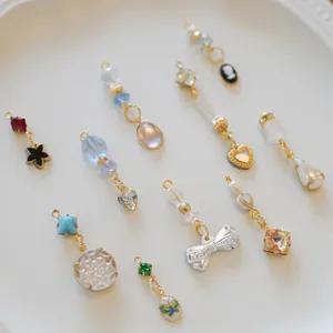 Assorted elegant jewelry pendants with bow, heart, and gemstone beads on white ceramic plate