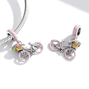Gros plan de charms vélo en émail rose avec détails de panier de fleurs sur chaîne.