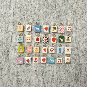 Assorted hand-painted ceramic charms featuring fruits and animals on stone surface