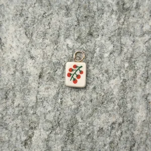 Detailed macro view of a mini ceramic tomato pendant with a gold stainless steel ring