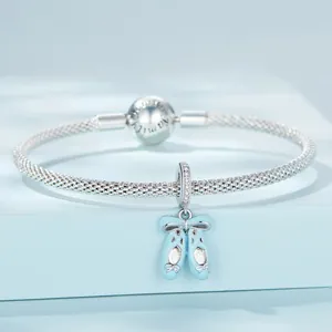 Gros plan d'un bracelet en maille d'argent avec un pendentif ballerines bleu clair.