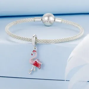 Gros plan d'un bracelet à breloques en argent avec un pendentif flamant rose sur fond bleu