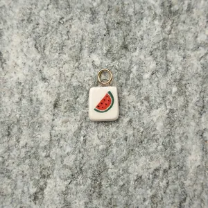 Close-up of white ceramic watermelon pendant with gold ring on stone background