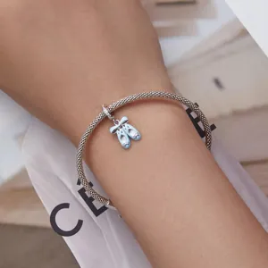 Détail d'un bracelet en maille argentée orné d'une breloque chaussons de danse en émail bleu