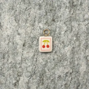Close-up of a white rectangular pendant featuring a cute cherry design on stone background