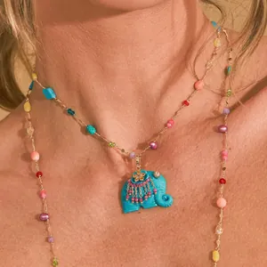 Close-up of a colorful beaded necklace featuring a turquoise elephant pendant on a model.