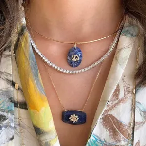 Close-up view of layered gold necklaces with blue stone pendants and crystal accents.