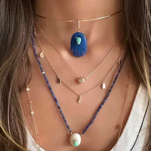 Close-up of layered necklaces featuring blue Hamsa hand and gemstone pendants