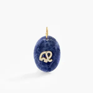 Detailed view of an oval blue gemstone pendant featuring a gold pavé diamond elephant charm