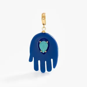 Detailed macro view of a blue Hamsa hand pendant with a teardrop turquoise stone inlay.