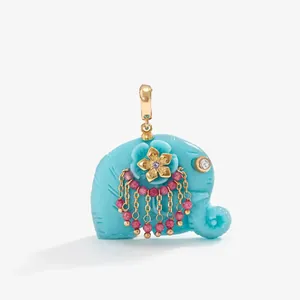 Detailed view of a turquoise elephant pendant with golden flower and pink beaded tassels.