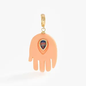 Detailed macro view of a peach Hamsa hand jewelry pendant with blue teardrop stone inlay