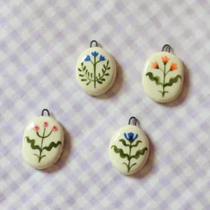 Detail view of four handmade floral ceramic pendants on purple checkered cloth