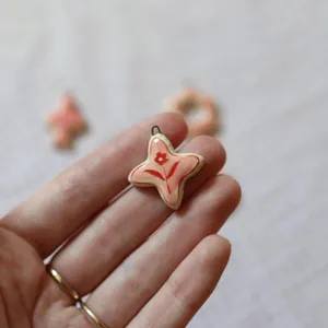 Close-up of a pink star-shaped ceramic pendant with a delicate red flower pattern