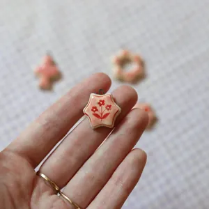 Close-up of a star-shaped pendant with red flower pattern on a ceramic-style finish
