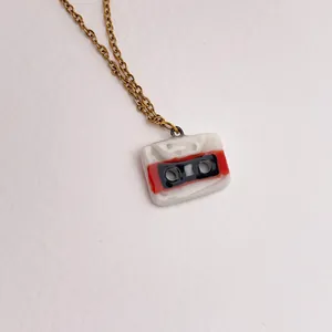 Détail d'un pendentif cassette vintage sur une délicate chaîne de collier dorée