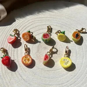 Colección de dijes de frutas realistas con cierres de langosta dorados sobre madera