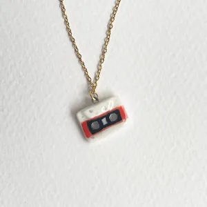 Détail d'un pendentif de cassette miniature unique sur une chaîne de collier dorée.